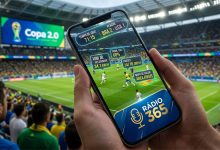 Mãos segurando um smartphone moderno em um estádio lotado. A tela do celular exibe uma interface de Realidade Aumentada com estatísticas de jogo (velocidade do jogador, mapa de calor e probabilidade de gol) sobrepostas ao gramado da Copa 2026. No canto inferior da tela do celular, o logo da Rádio 365 está nítido e em destaque.